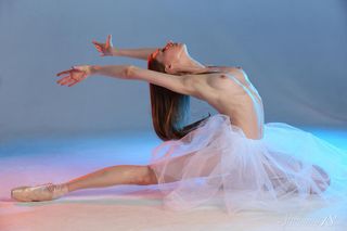 Балерина в пачке показывает на голубом фоне упругую задницу и чистую писечку